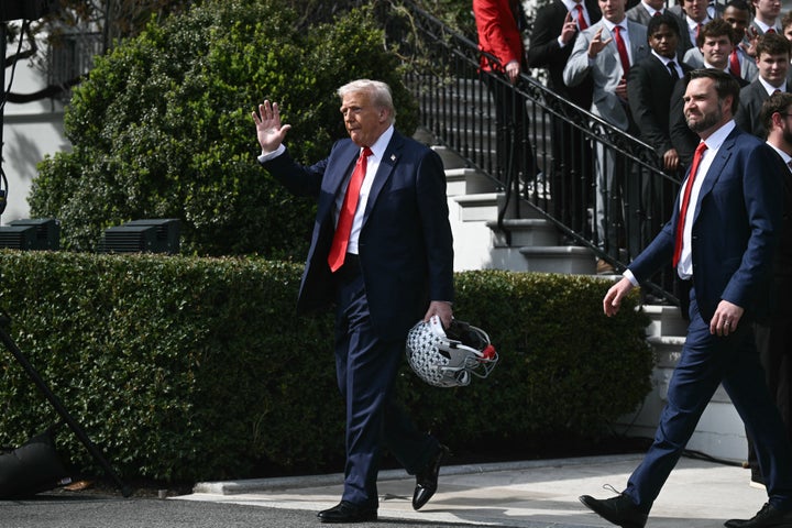 President Donald Trump (left) carries an Ohio State football helmet as Vice President JD Vance (right) follows him after a ceremony for the college football national champion Buckeyes on the South Lawn of the White House in April 2025.