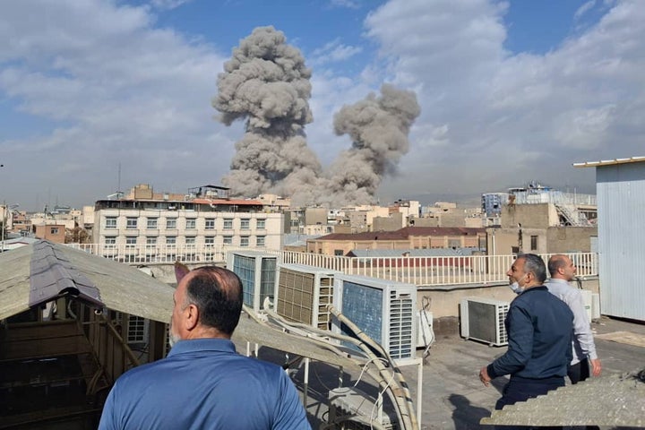 Les gens regardent la fumée s’élever à l’horizon après une explosion à Téhéran, en Iran, samedi.