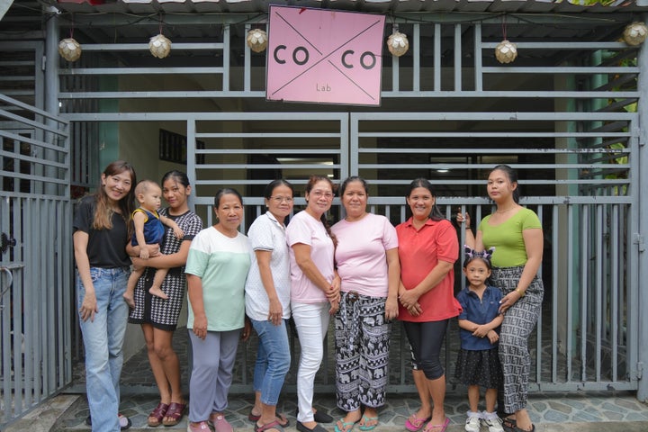 フィリピンにあるファッションスクール「coxco Lab」の前に立つ、現場責任者の小村萌さん(左)と生徒たち