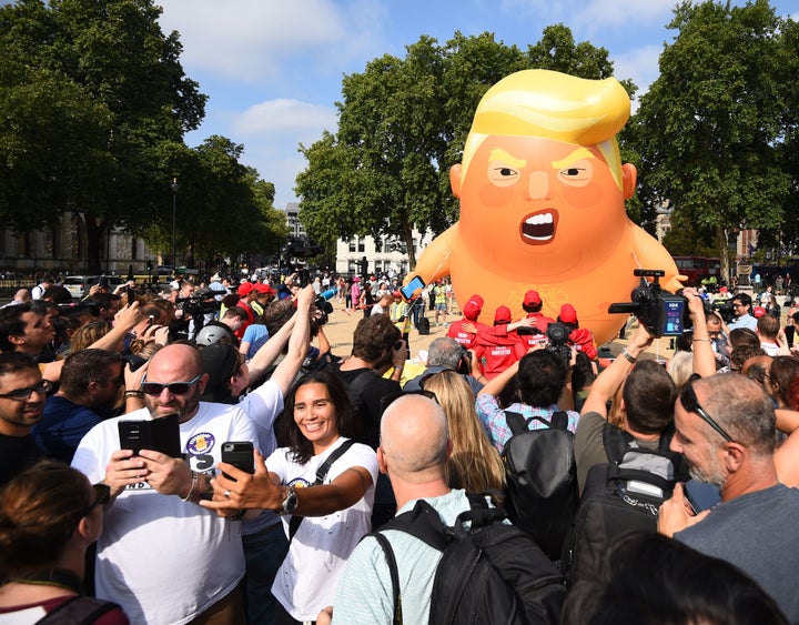 People take a selfie as a "Baby Trump" balloon rises after being inflated in London's Parliament Square, as part of the protests against a visit of U.S. President Donald Trump to the U.K.