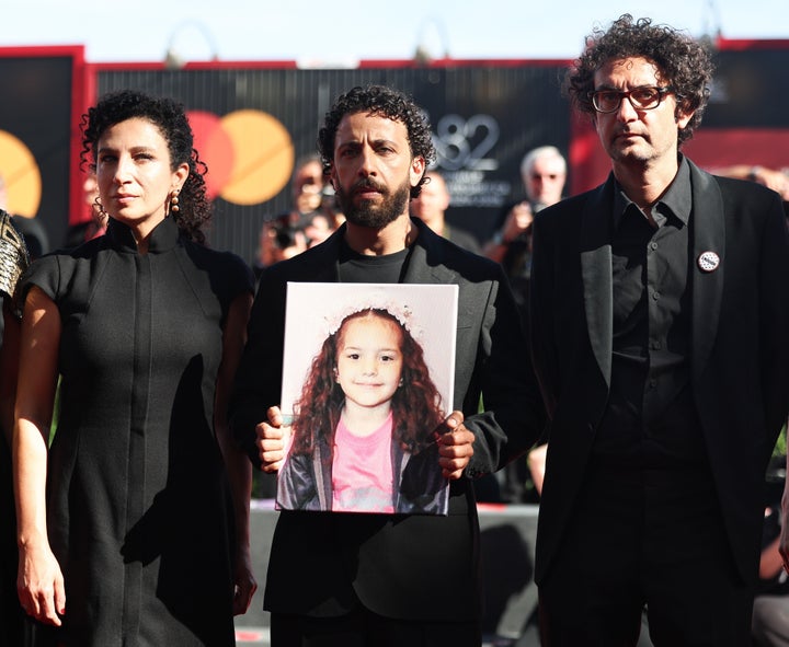 "The Voice of Hind Rajab" actor Motaz Malhees (center) holds a photo of Hind Rajab as fellow actor Clara Khoury (left) and producer Nadim Cheikhrouha (right) pose alongside him on the red carpet of the movie's premiere at the Venice Film Festival in September.
