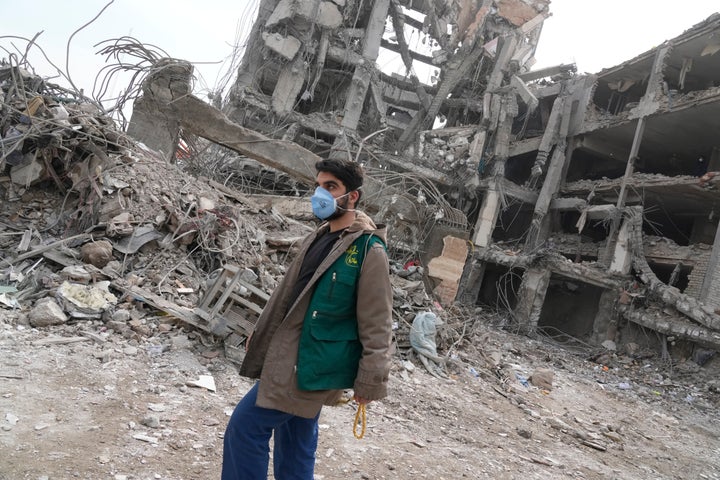 A volunteer walks in front of a residential building in Tehran, Iran, Thursday, March 12, 2026, after it was damaged on Sunday during the U.S. - Israeli air campaign. (AP Photo/Vahid Salemi)