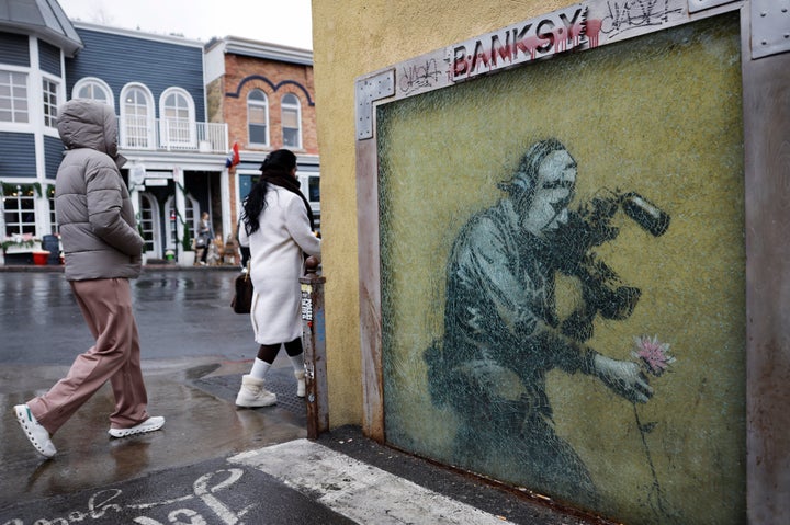 PARK CITY, UTAH - FEBRUARY 09: People walk past a Banksy piece as light snow falls as a significant weather pattern shift begins to deliver snow to Utah's mountains in the region on February 9, 2026 in Park City, Utah. A snow drought and warmer weather across Utah and much of the Western United States resulted in Utah receiving only around one-third of its normal early February snowpack. Ski resorts at higher elevations have received sufficient snowfall but those at lower elevations in the region have thus far been forced to make artificial snow all season. The state relies on mountain snowpack for around 95% of its water supply. (Photo by Mario Tama/Getty Images)