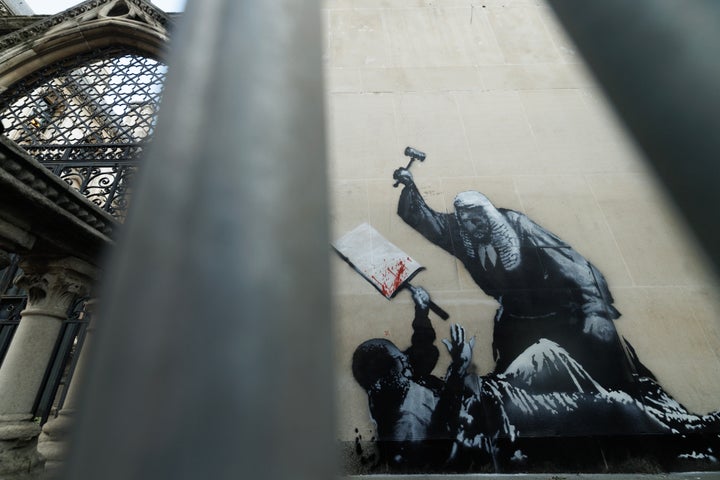 LONDON, ENGLAND - SEPTEMBER 09: A new Banksy mural, remains covered outside the Royal Courts of Justice, on September 09, 2025 in London, England. Banksy posted a photograph of his latest mural on the side of the Royal Courts of Justice today, depicting a Judge beating a protester. Within hours of him posting the image the artwork had been covered over and guarded by security officers. (Photo by Dan Kitwood/Getty Images)