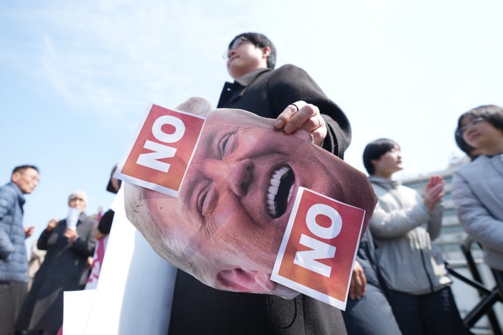 A man holds a picture of U.S. President Donald Trump after a news conference against Trump's demands to multiple countries to send warships to keep the Strait of Hormuz open, near the U.S. Embassy in Seoul, South Korea, on March 16.