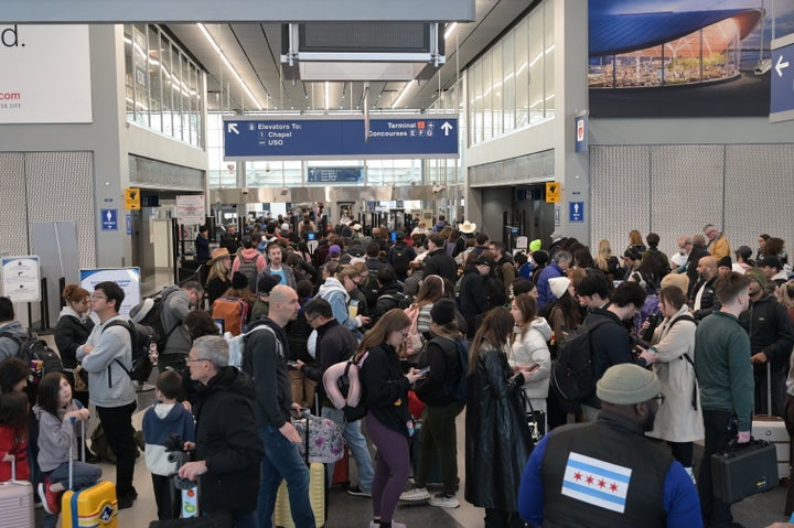 A general view shows hundreds of travelers navigating dense queues and crowded terminal walkways at O'Hare International Airport, in Chicago, Illinois, United States, on March 16, 2026. The massive surge in passenger volume at the major global hub results in significant delays and checkpoint bottlenecks during a peak spring travel period, leaving many frustrated passengers checking monitors as they race to make connecting flights.