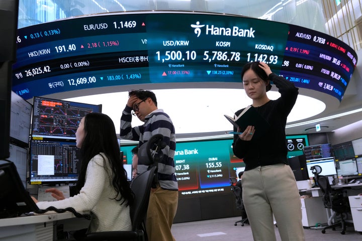 Currency traders work near a screen showing the Korea Composite Stock Price Index (KOSPI), top center, and the exchange rate between the US dollar and South Korean won, top center left, in the foreign exchange trading room at Hana Bank headquarters in Seoul, South Korea, on March 19, 2026.