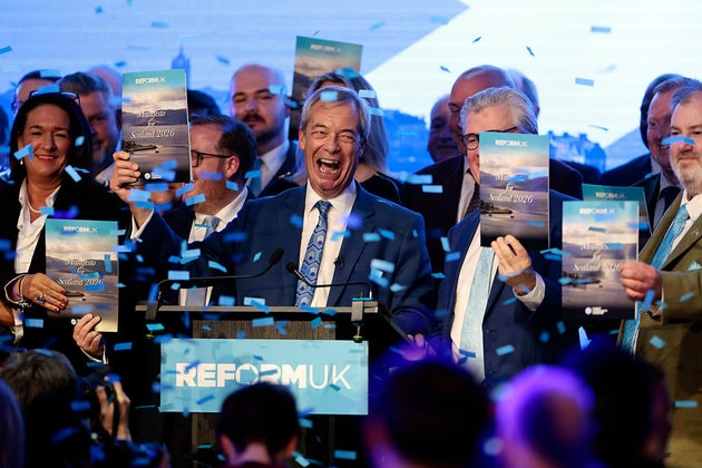 Nigel Farage holds up a copy of Reform's Scottish election manifesto surrounded by the party's candidates.