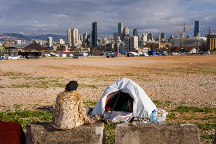 A displaced woman sits next her tent in an unofficial camp along Beirut's seafront on March 22, 2026. The Israeli military launched a wave of strikes on on the Lebanese capital after urging residents to evacuate.