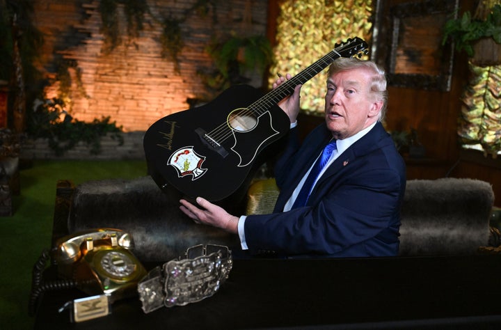 Trump holds a replica of an Elvis Presley guitar after signing it during a visit to Graceland on March 23.