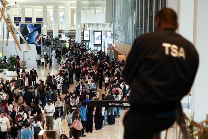 A TSA agent looks on as passengers line up to go through security at New York's LaGuardia airport on March 22, 2026.