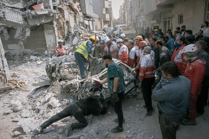 First responders inspect a destroyed car at the site of a residential building hit in a nighttime attack during the US-Israeli military campaign in Tabriz, East Azerbaijan province, northwest Iran, March 24, 2026.