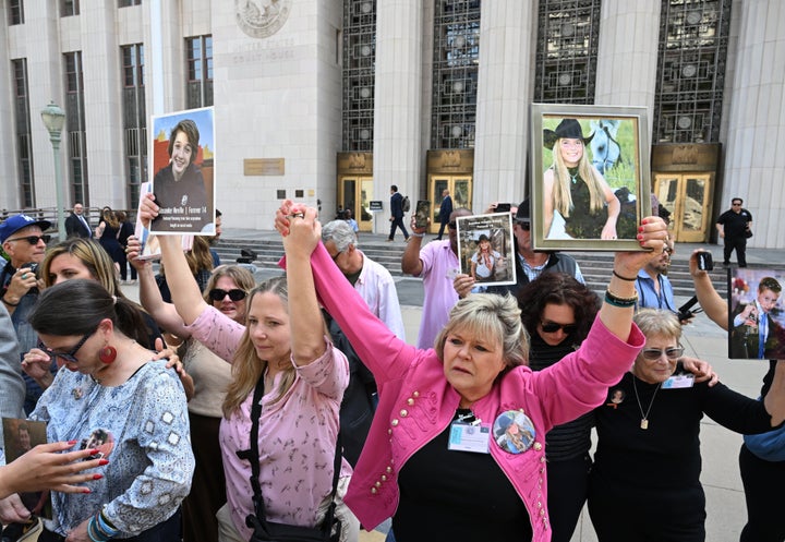 Family members hold up photos after the verdict in a landmark trial over whether social media platforms deliberately addict and harm children at Los Angeles Superior Court, Wednesday, March 25, 2026, in Los Angeles. (AP Photo/William Liang)