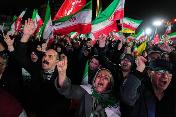 Pro-government supporters chant slogans and wave Iranian flags during a rally, in a square in western Tehran, Iran, on March 25, 2026.