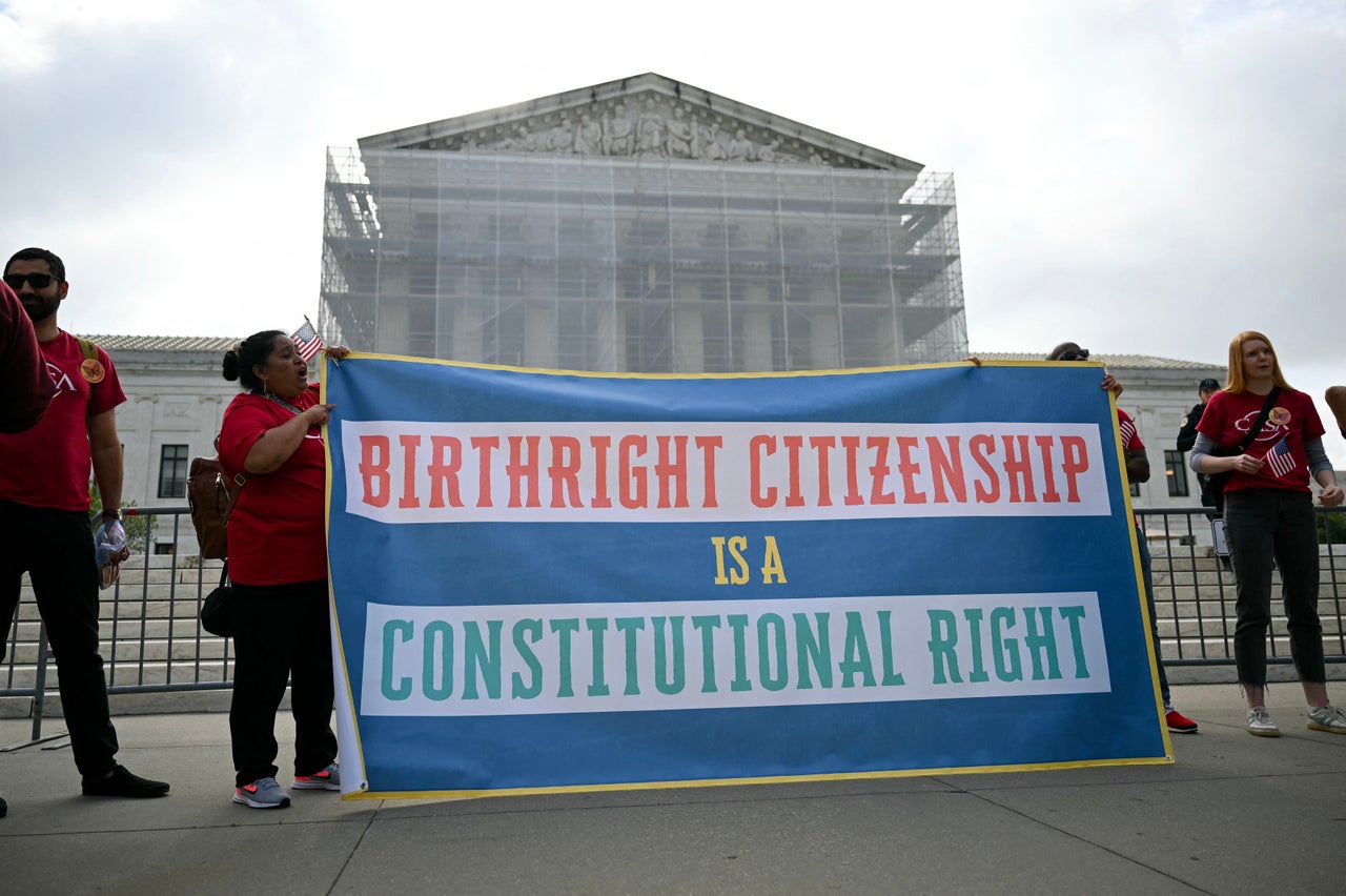 People hold a sign as they participate in a protest outside the U.S. Supreme Court over President Donald Trump’s move to end birthright citizenship as the court hears arguments over the order in Washington, D.C., on May 15, 2025. Trump issued an executive order on his first day in office seeking to limit birthright citizenship for children whose parents are in the United States illegally or on temporary visas, but it has been blocked in multiple appellate courts. He appealed the case to the Supreme Court on March 13.