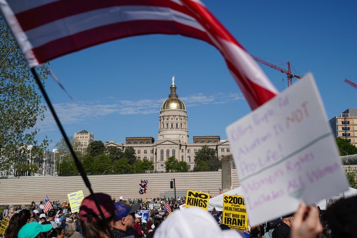 People hold US flags and signs as they march near the Georgia state Capitol building during the "No Kings" national day of protest in Atlanta, Georgia.