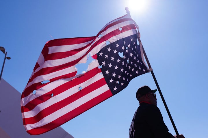 A man holds an inverted US flag with holes in it as he and others march across the Frederick Douglass Bridge during the "No Kings" national day of protest in Washington, D.C.