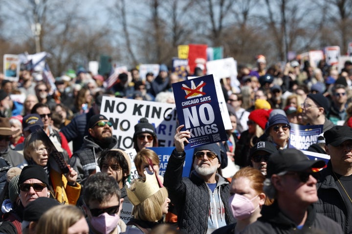 People hold signs as they rally at Grant Park during the "No Kings" national day of protest in Chicago on March 28, 2026. Nationwide protests against US President Donald Trump are expected Saturday as millions of people vent fury over what they see as his authoritarian bent and other forms of cruel, law-trampling governance. It is the third time in less than a year that Americans will take to the streets as part of a grassroots movement called "No Kings," the most vocal and visual conduit for opposition to Trump since he began his second term in January 2025. (Photo by KAMIL KRZACZYNSKI / AFP via Getty Images)