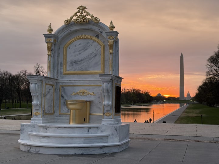 “It stands as a tribute to an unwavering visionary who looked down, saw a problem, and painted it gold,” reads the 10-foot-tall throne hailing Trump for renovating a White House bathroom.
