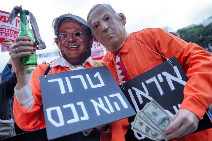 Protesters wearing orange jumpers and masks depicting Israeli Prime Minister Benjamin Netanyahu and his far-right National Security Minister Itamar Ben Gvir pose during an anti-war demonstration in Tel Aviv's Dizengoff Square on March 19, 2026.