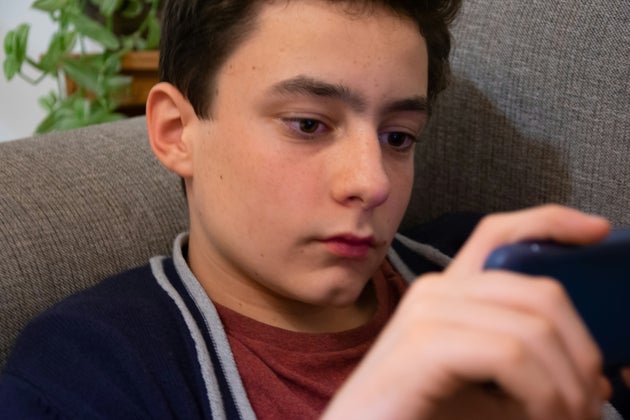 A teenage boy looks at a mobile device