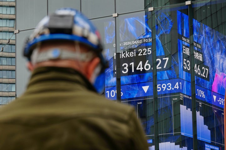 A person stands in front of an electronic stock board showing Japan's Nikkei index at a securities firm Thursday, April 2, 2026, in Tokyo.