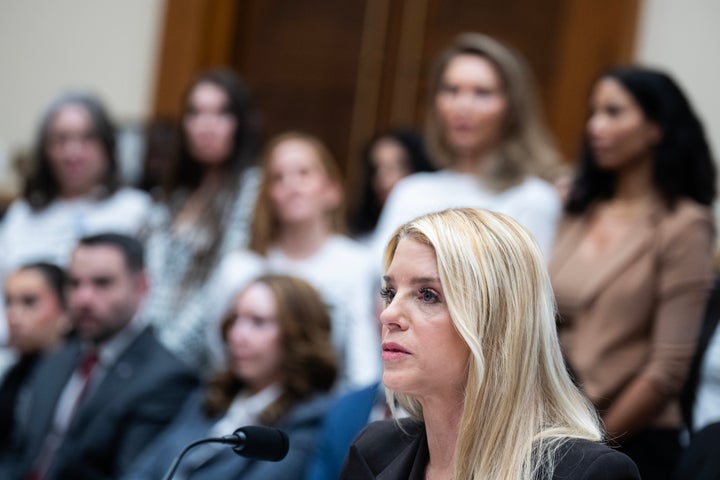 Then-Attorney General Pam Bondi testifies as Jeffrey Epstein survivors stand in the background on Feb. 11, 2026. 