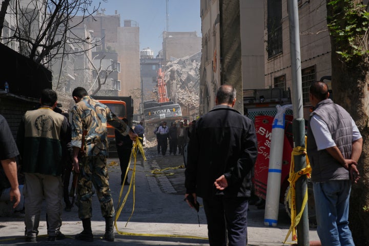 Bystanders watch from a distance as rescue teams and first responders work at the site of a strike that, according to a security official at the scene, destroyed half of the Khorasaniha Synagogue and nearby residential buildings in Tehran, Iran, on April 7, 2026.