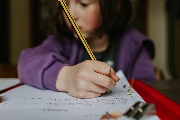 A little girl holds a pencil while she does her homework.