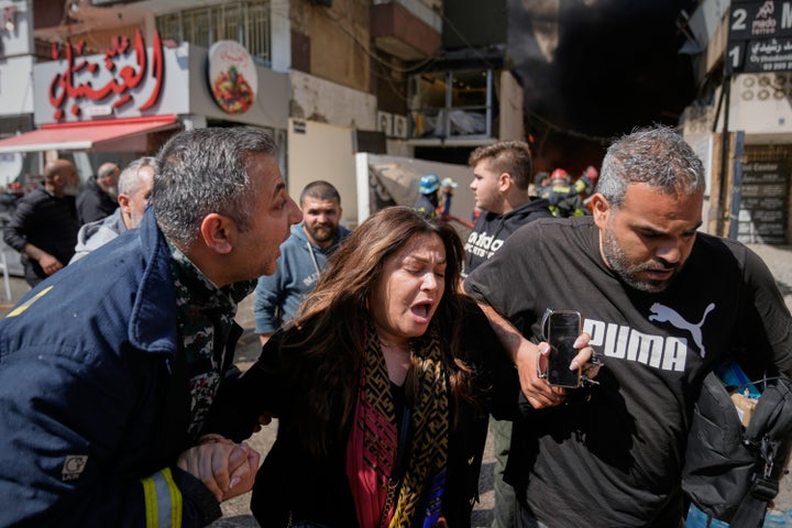 A woman is assisted at the site of an Israeli airstrike that struck an apartment building in Beirut, Lebanon, Wednesday, April 8, 2026. (AP Photo/Bilal Hussein)