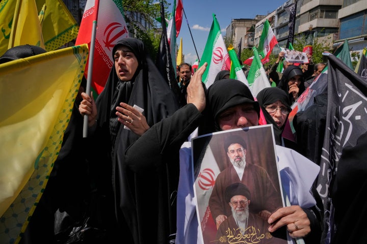 A woman holds a picture depicting Iran's Supreme Leader Mojtaba Khamenei, top, and his father, the slain Supreme Leader Ayatollah Ali Khamenei, as government supporters gather to mark the 40th day since his death in Tehran, Iran, on April 9, 2026.