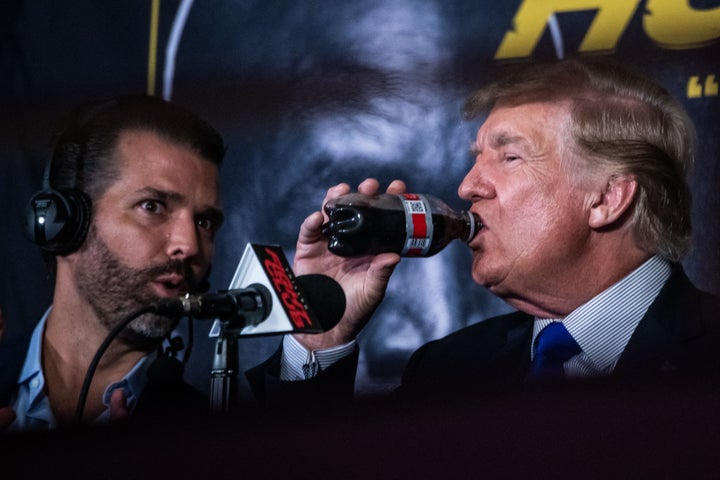 President Donald Trump drinks a soda as he hosts the Holyfield vs Belford boxing match live in 2021, next to his son Donald Trump Jr.
