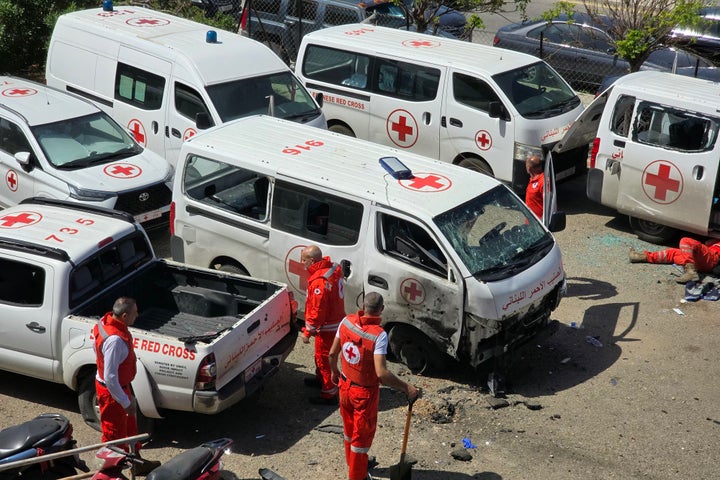 Lebanese Red Cross volunteers inspect the damage to their ambulances at the site of an Israeli drone strike that targeted their headquarters in Tyre on April 13, 2026. 