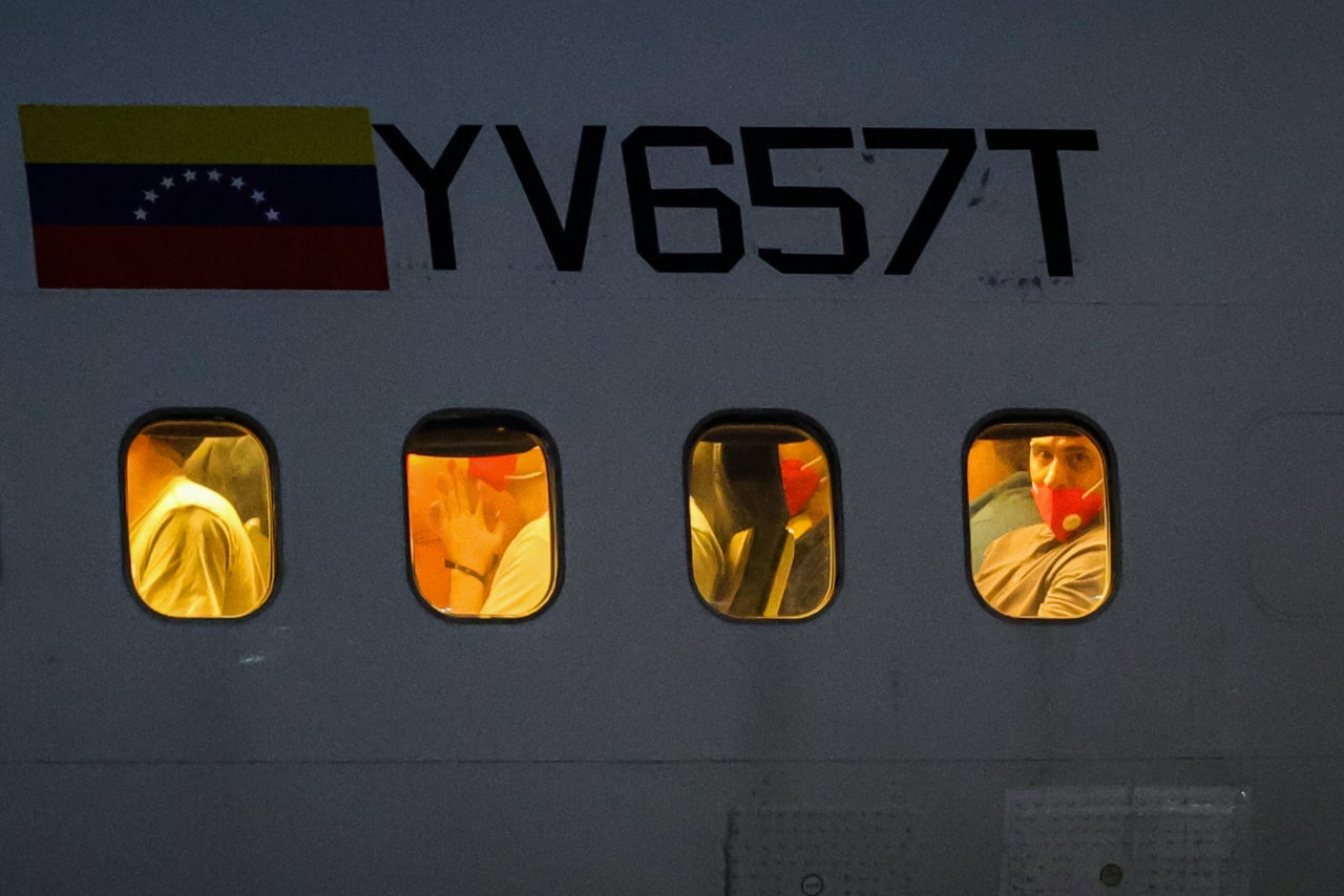 A detained Venezuelan looks through the windows of the plane transporting detainees as part of an exchange agreement between Venezuela and the United States on July 18, 2025. The Venezuelans had been sent to El Salvador in March after President Donald Trump invoked the 1798 Alien Enemies Act to deport presumed "Tren de Aragua" gang members without passing under normal immigration processes.