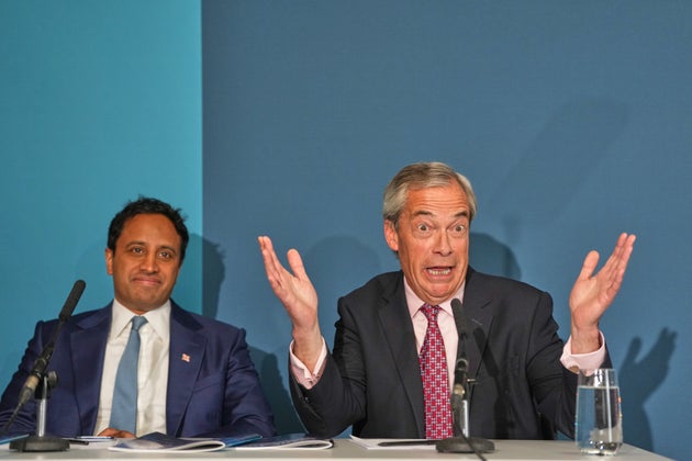 Reform leader Nigel Farage, leader of the Reform UK party, right, sits with Zia Yusef as he speaks at a press conference in London, Monday, April 13, 2026. (AP Photo/Kirsty Wigglesworth)