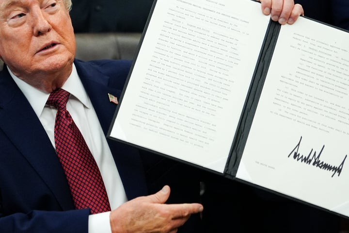 President Donald Trump holds up a signed executive order in the Oval Office on April 18, 2026.