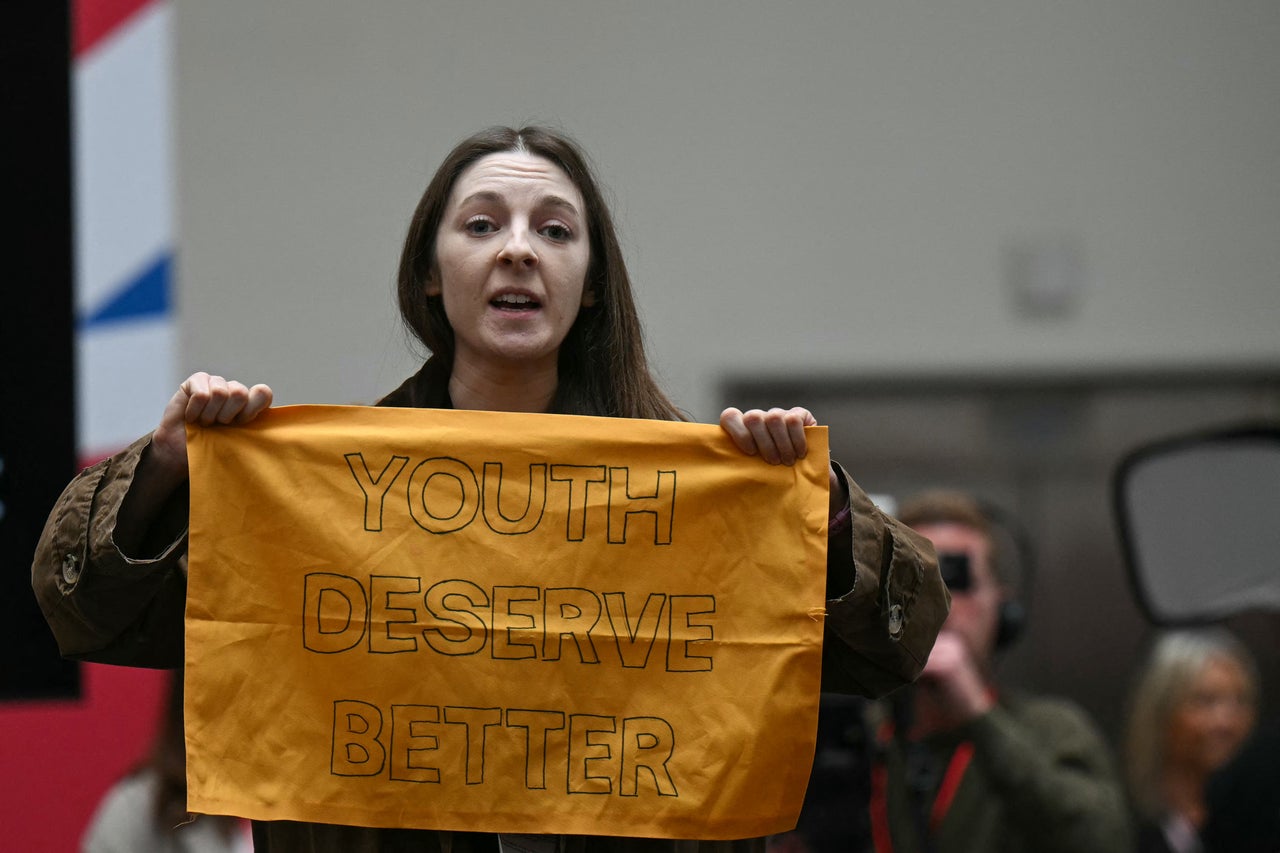 A demonstrator gets up and shows a banner reading "Youth Deserve Better" during the launching speech of Britain's main opposition Labour Party election manifesto booklet, in Manchester, on June 13, 2024 