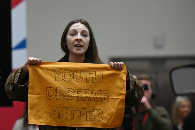 A demonstrator gets up and shows a banner reading 