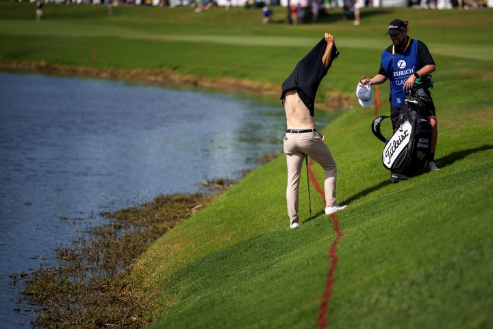Brennan takes off his shirt before trying to hit his ball from the floating debris on the 18th hole.