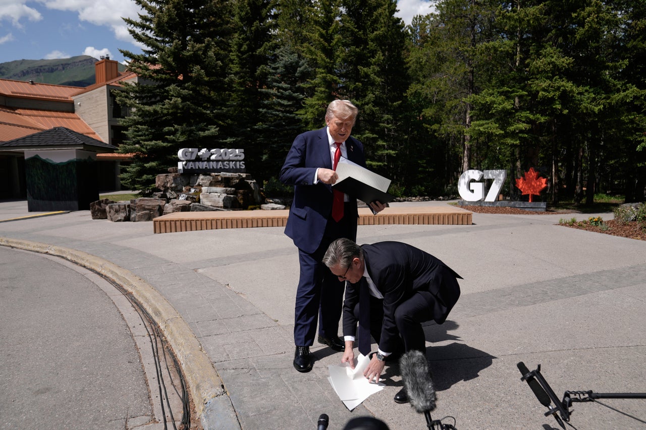 Starmer picks up the UK-US trade agreement papers dropped by Trump before speaking to the media at the G7 summit in Kananaskis, Alberta, Monday June 16, 2025.