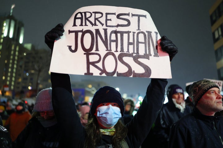 A protester holds a sign reading "ARREST JONATHAN ROSS" during a rally for Renee Good on Jan. 8, 2026, in Minneapolis, after she was fatally shot the day before. 