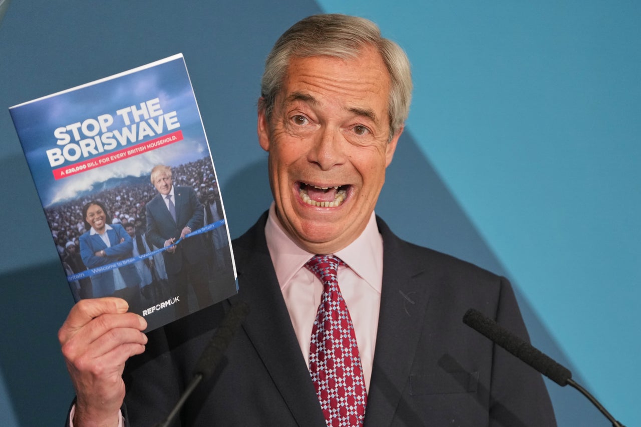 Nigel Farage leader of the Reform UK party holds up a booklet during a press conference in London, Monday, April 13, 2026.