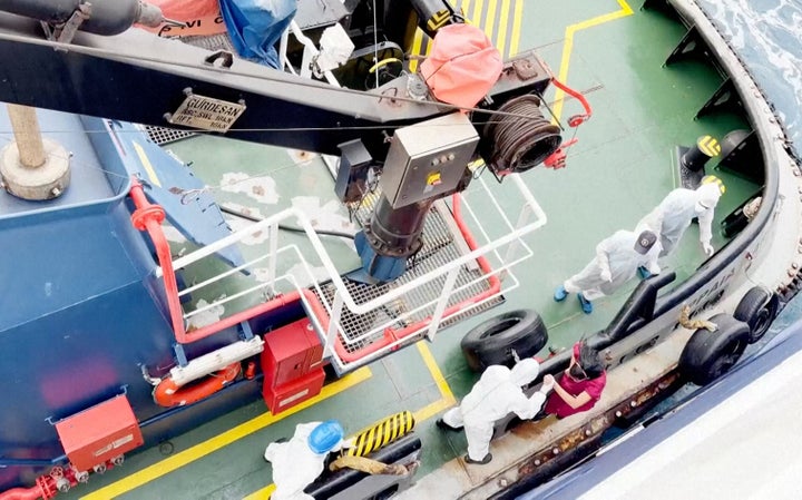 Health workers wearing personal protective equipment get off the Dutch-flagged MV Hondius, a cruise ship carrying nearly 150 people, as it remains off Cape Verde on Monday.