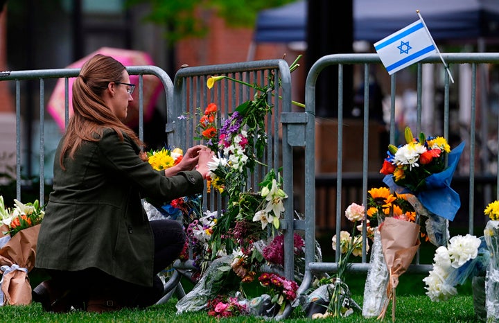 A woman places a bouquet of flowers at a makeshift memorial for victims of an attack outside of the Boulder County, Colo., courthouse Tuesday, June 3, 2025, in Boulder, Colo. (AP Photo/David Zalubowski, File)