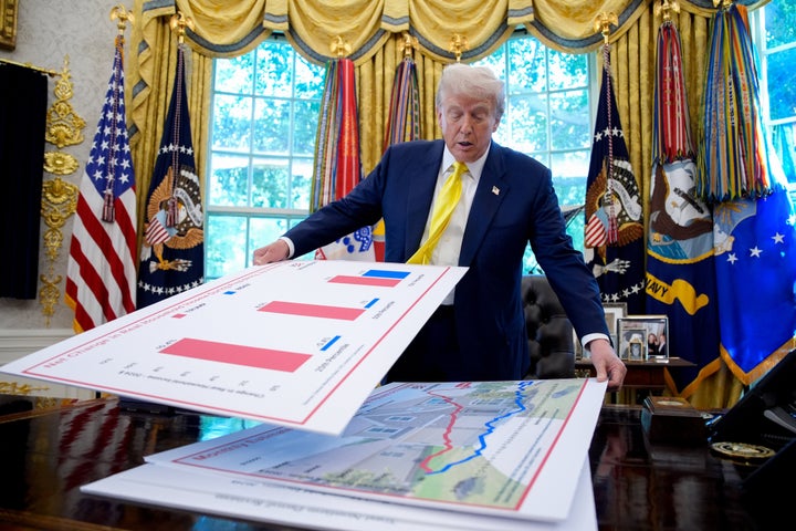 President Donald Trump really likes charts. Here he's seen moving around large printouts of charts in the Oval Office on Aug. 7, 2025.