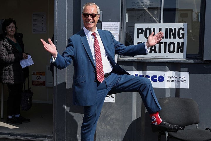 Reform UK leader Nigel Farage poses to show off his socks as he visits a polling station in Walton-on-the-Naze.