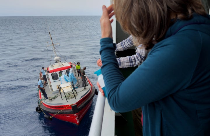 Passengers on the the hantavirus-stricken cruise ship, MV Hondius, watch epidemiologists board the boat in Praia, during their voyage to Spain's port of Tenerife, May 6, 2026. (AP Photo)
