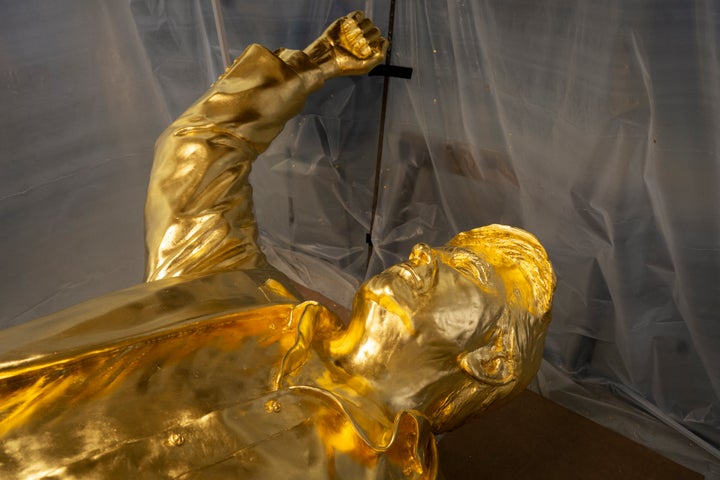 The bust portion of a 15-foot bronze statue of US President Donald Trump, coated in gold leaf, lies on its back in the studio (Photo by Eli Hiller / AFP via Getty Images)