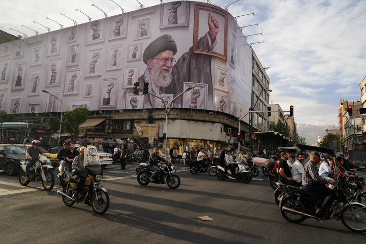Motorcycles pass a billboard depicting the late Iranian Supreme Leader Ayatollah Ali Khamenei, who was killed in US and Israeli strikes on February 28, with a framed fist among his supporters in downtown Tehran, Iran, on Wednesday, May 6, 2026. (AP Photo/Vahid Salemi)