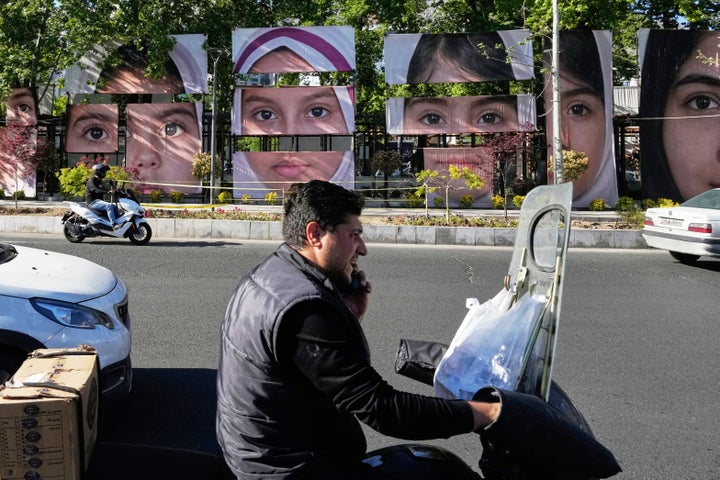 Vehicles drive past banners showing portraits of the school children who were killed during a strike on a school in southern town of Minab on Feb. 28, at Tajrish square in northern Tehran, Iran, Sunday, May 10, 2026. (AP Photo/Vahid Salemi)